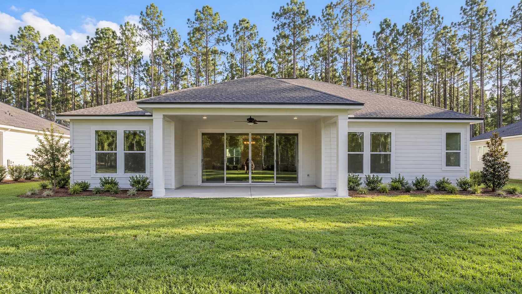 Newly built Yulee home with fresh sod and a line of pine trees behind the backyard